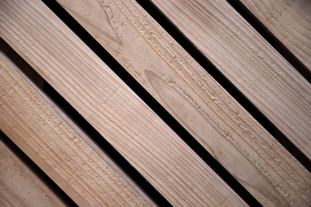 Four wooden planks with a light finish are arranged diagonally, with narrow black gaps between them—an ideal touch for a modern garden studio. The wood grain and texture are visible on each plank.