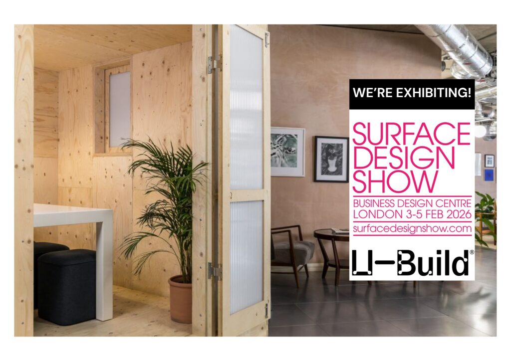 A modern and minimalistic office space fitted with U-Build plywood cubicles, white table, chairs, green plants, and framed artwork. An overlay announces Li-Build is exhibiting at the Surface Design Show in London, 3–5 February 2026.