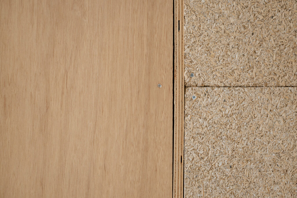 Close-up of two wood panels side by side: smooth plywood on the left and textured oriented strand board (OSB) on the right, both fastened with screws—ideal for Sustainable Ventures or sustainable business projects in Manchester.