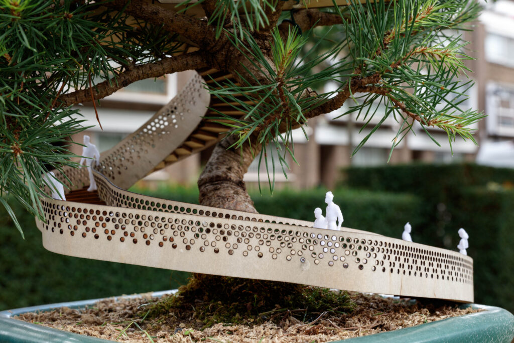 A model of a bonsai tree with a miniature walkway winding around its trunk, featuring tiny human figures walking on the path—perfect as a unique display piece for any bonsai exhibition.